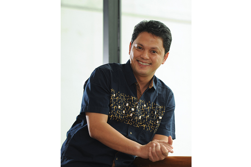 A man wearing blue patterned shirt smiling